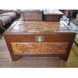 A Chinese camphorwood chest, rectangular with figural carved panels, 101cm wide, 53cm deep, 59cm