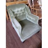 An Edwardian upholstered low armchair with turned legs