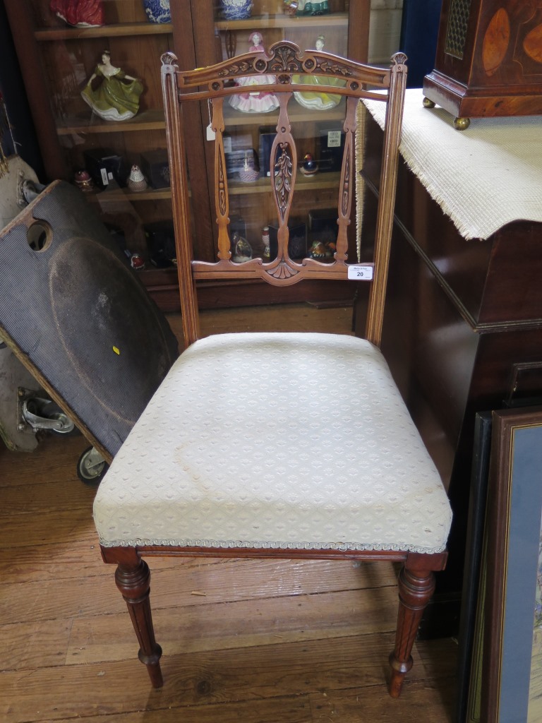 A pair of Edwardian walnut bedroom chairs, the pierced carved railbacks above stuffover seats on