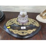 A Victorian ebonised and brass ink standish of oval form with hexagonal pressed glass inkwell,