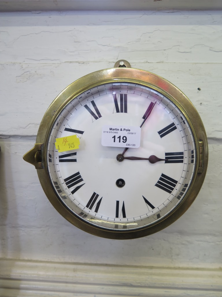 A brass ship's clock, with enamel dial and single train movement 18.5cm diameter