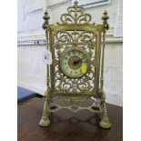 An Edwardian brass table timepiece, in the form of a screen, with pierced foliate scrolls, on a