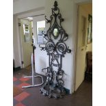 A Victorian style cast iron hall stand, of floral scroll form with hinged oval mirror and umbrella