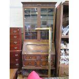 A panelled oak bureau bookcase, with glazed top over a sloping fall above two short and one long