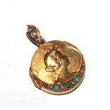 A small 15 carat gold locket with the head of a young girl in relief, the locket set with
