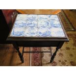 An ebonised side table, with Delft tiled top (most cracked) over a frieze drawer on turned legs