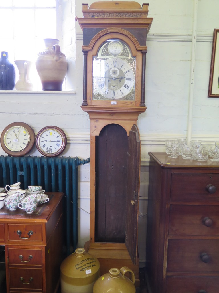 A George III pine longcase clock, the caddy top over a brass dial with gilt metal mask spandrels,