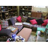 A stained wicker corner sofa, made up of five sections, with red and brown cushions , each side