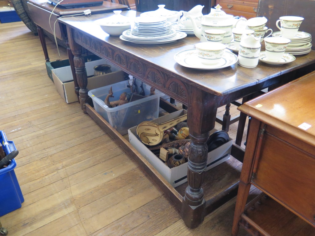 An oak refectory table, the rectangular top over a lunette carved frieze and fluted turned legs on