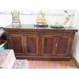 A stained walnut side board with wiggle work mouldings, comprising two pairs of panelled doors