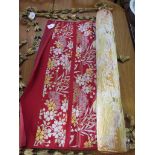 A Japanese red ground roll of fabric, with silver and gold coloured thread, depicting a repeating