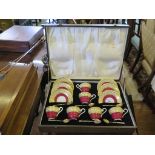 A cased set of Aynsley coffee cans and saucers in red gilt banded decoration with silver enamel