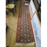 A long Indian style runner, with allover palmette design within a terracotta border 599cm x 59cm