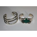 Two silver bangles one set with a green stone