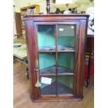 A George III corner cupboard, the glazed door enclosing shaped shelves 70cm wide, 99cm high