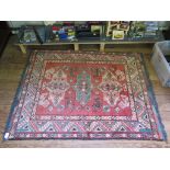 A Kazak rug with three green and ivory medallions on a red field with serrated border, 137cm x