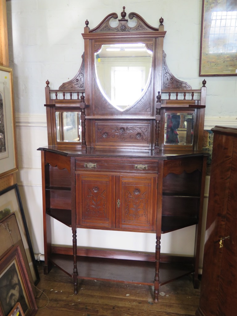 An Edwardian walnut mirror-back side cabinet, the shield shape mirror over mirror-back shelves,