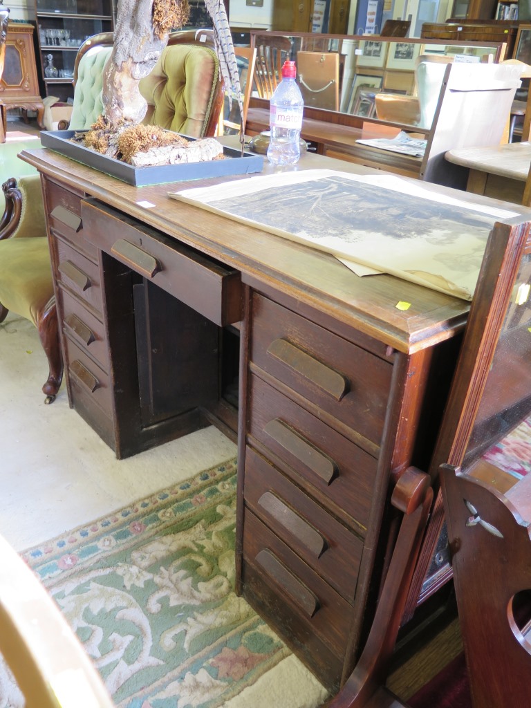 An oak kneehole desk, the central drawer over cupboard doors to the kneehole flanked by four drawers