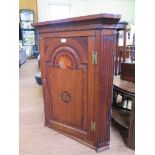 A George III inlaid oak corner cupboard, the arch panel door with sunburst inlay flanked by fluted