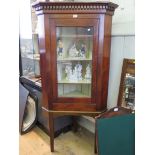 A George III style mahogany corner cupboard, the dentil cornice over a glazed door on square section