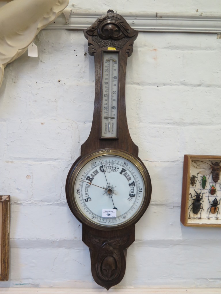 An Edwardian stained oak banjo barometer, with foliate carving, mercury thermometer and aneroid