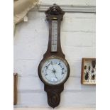 An Edwardian stained oak banjo barometer, with foliate carving, mercury thermometer and aneroid