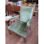 An Edwardian oak armchair, with scroll back, green upholstery and turned legs on castors