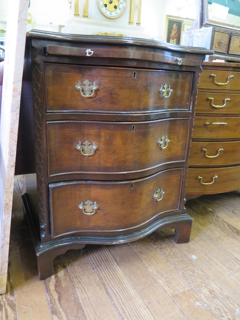 A George III style walnut serpentine chest with brushslide three long graduated drawers, blind