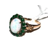 A 14 carat gold ring, set with a central opal with cabochon emeralds around