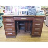 An oak kneehole desk, the central drawer over cupboard doors to the kneehole flanked by four drawers