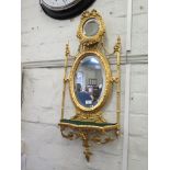 A French giltwood wall mirror, the oval bevelled plate with floral swags over a shelf on floral