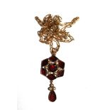 A gold pendant set with flat cut garnets and seed pearls on gold plated chain