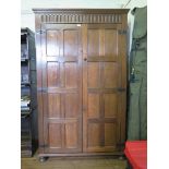 An oak hall robe, the fluted frieze over a pair of panelled doors on pad feet, 112cm wide