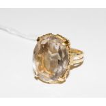 A gold colour metal ring with basket work decoration, set with a large smoky quartz stone