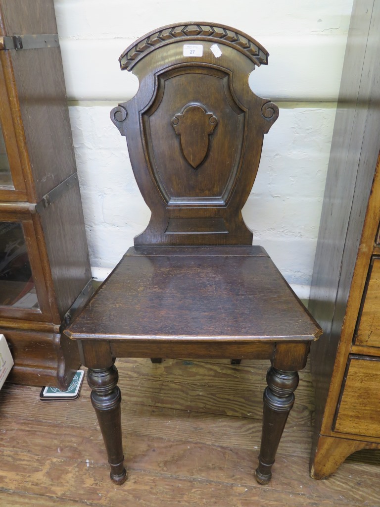 An oak hall chair, with shield shape back and turned legs