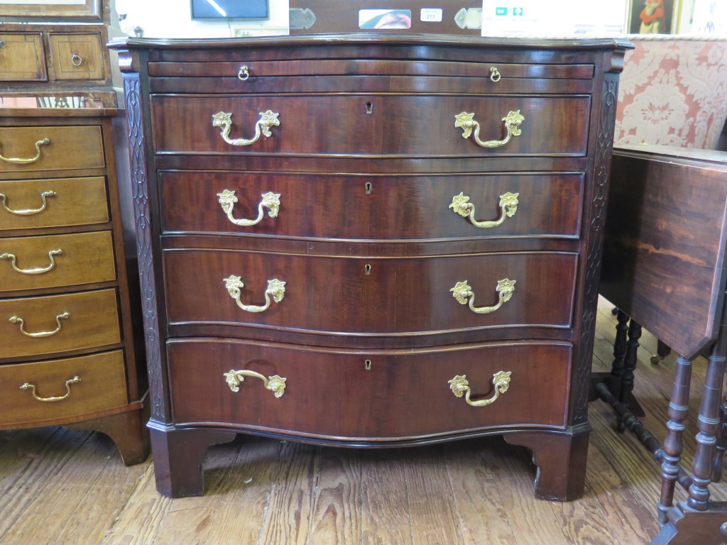 A George III style serpentine chest, with brush slide and four graduated drawers flanked by blind