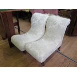 A pair of Victorian upholstered low nursing chairs, with scroll back and seat on turned legs and