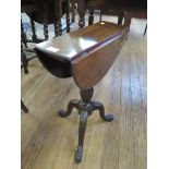 A George III style mahogany tripod table, the rotating oval top with drop leaves over a ribbon