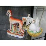 Two Victorian Staffordshire figures of dogs holding rabbits 19.5cm and 29cm high, another figure