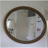 An egg moulded giltwood oval mirror, 69cm wide, another giltwood oval mirror 55cm high and a pine