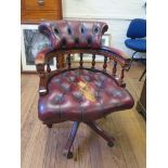 A leather upholstered swivel office armchair, with button upholstery and turned supports