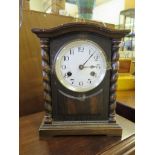 An Edwardian oak mantel clock, with barley-twist supports and enamelled dial, the twin train