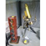 A brass and black metal monocular microscope with Watson lens and adjustable aperture under the