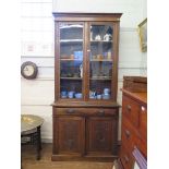An Edwardian oak bookcase cabinet, the twin glazed doors over a long frieze drawer and a pair of