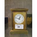 An Edwardian brass carriage clock, the enclosed arched top over a circular enamel dial, the twin