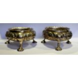 A PAIR OF VICTORIAN SILVER SALT CELLARS with foliate decoration, standing on shell feet