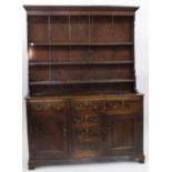 AN 18TH CENTURY OAK WELSH DRESSER fitted with fielded panel door and standing on shaped bracket