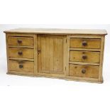 A VICTORIAN PINE DRESSER BASE with central panelled door and six short drawers, all with turned knob