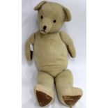 A 20TH CENTURY STRAW FILLED TEDDY BEAR with a stitched nose, mouth and glass eyes, possibly a