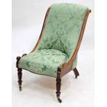 A VICTORIAN MAHOGANY FRAMED GREEN UPHOLSTERED LOW CHAIR with reeded front legs and brass castors